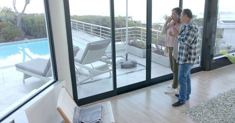 Diverse Couple Enjoying Tranquil Poolside View from Elegant Home