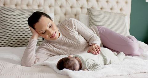 Mother gently watching sleeping infant at home in cozy room
