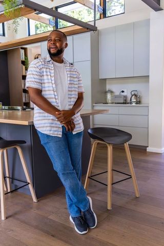 African american man relaxing at kitchen island in modern minimalist home interior
