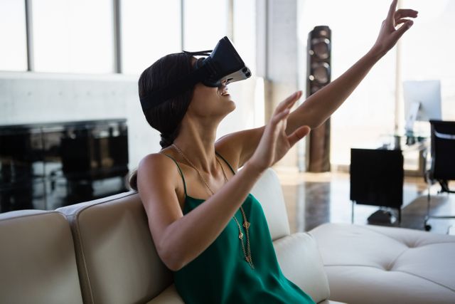 Businesswoman using VR headset in a modern office environment, showcasing the integration of advanced technology in the workplace. Ideal for illustrating concepts of innovation, digital transformation, and immersive experiences in professional settings. Can be used for articles, presentations, and marketing materials related to technology, business innovation, and modern office environments.