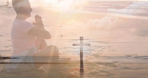 Senior Woman Praying on Beach with Crucifix Overlay Symbolizing Faith