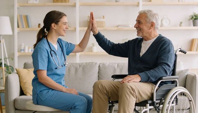 Nurse high-fiving senior man in wheelchair at home care visit conveying trust and warmth