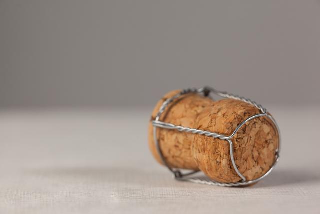 This image shows a close-up of a champagne cork with a wire cage on a white background. Ideal for use in holiday, celebration, and party-themed designs. Perfect for advertisements, invitations, and festive event promotions.