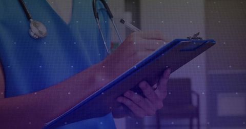 Doctor in Blue Scrubs Taking Notes in Hospital Corridor