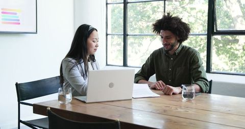Business Professionals Engaged in Office Discussion Near Window