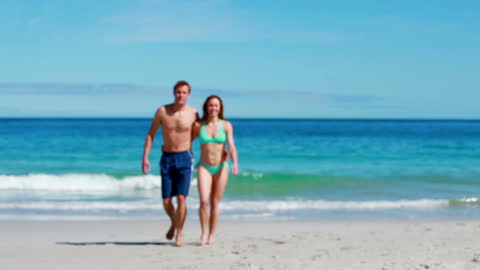 Smiling Couple Enjoying Beach Walk by Ocean