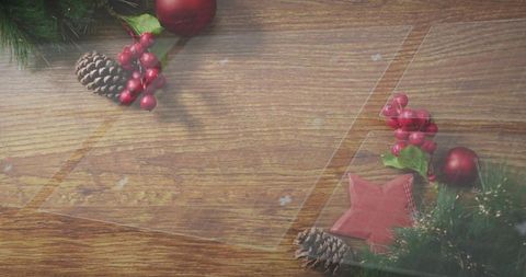 Festive flatlay featuring wooden table, star ornament, pinecones, red berries, baubles