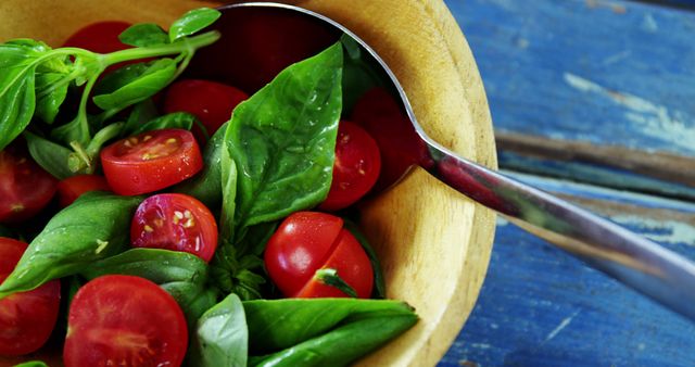 A colorful, healthy salad with cherry tomatoes and basil is presented in a wooden bowl. - Download Free Stock Photos Pikwizard.com