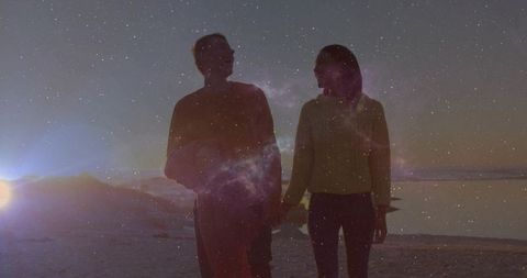 Walking couple holding hands on twilight beach with starry nebula overlay, romantic silhouette