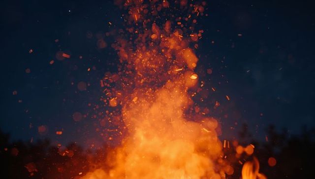 Blazing Bonfire with Flying Embers Illuminating Night Sky