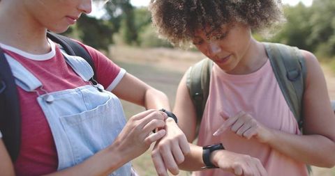 Diverse Friends Using Fitness Trackers Together Outdoors