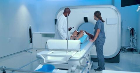 Radiology team positioning male patient for ct scan in modern diagnostic imaging suite