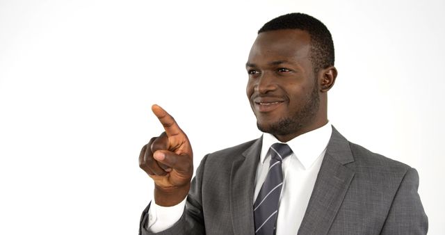 African American businessman in a suit is pointing towards something, with copy space. His confident gesture and professional attire suggest he's making an important point or presentation.
