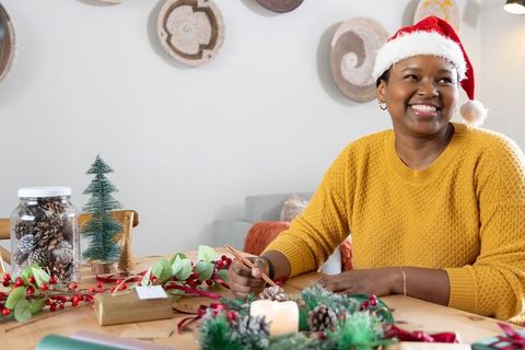 African american woman wearing santa hat writing gift tags at cozy holiday craft table