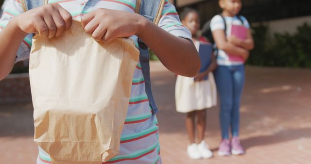 Child Holding Paper Bag with Schoolchildren in Background - Download Free Stock Images Pikwizard.com