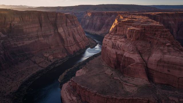 Sunlit sandstone promontory glowing over meandering river in desert canyon at sunset