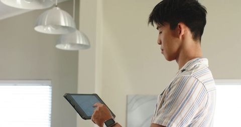 Asian man using tablet in minimalist contemporary interior with smartwatch
