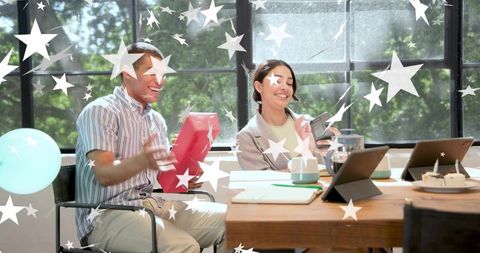 Coworkers celebrating birthday with surprise gift and treats in collaborative workspace
