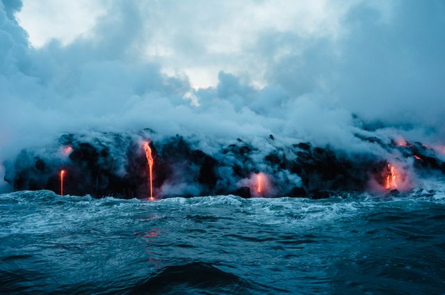 Volcanic lava flowing into the ocean creating steam clouds and dramatic scenery. Suitable for content related to geological activities, nature's power, travel, adventure, and educational materials on volcanic eruptions.
