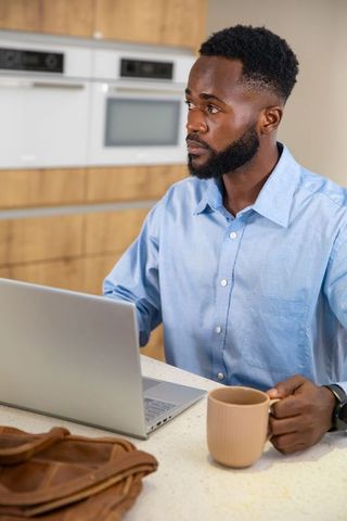 Focused Man Using Laptop while Enjoying Coffee at Home