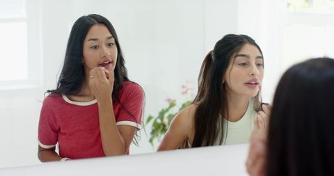 Young Women Enjoying Friendship While Applying Lipstick