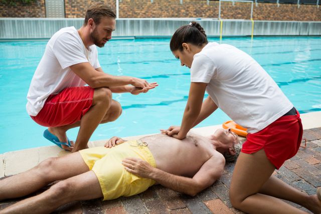 Lifeguards performing CPR on an unconscious senior man by the poolside. Useful for illustrating emergency response, lifesaving techniques, first aid training, and water safety protocols. Ideal for educational materials, health and safety campaigns, and training manuals.