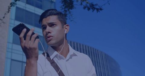 Young professional speaking into smartphone while commuting in urban business district