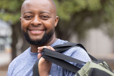 Confident african american student smiling while carrying backpack and wearing smartwatch