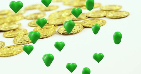 Floating green hearts over stacked gold coins conveying love, wealth and prosperity