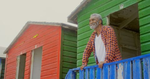 Happy senior man enjoying scenic view from colorful beach hut