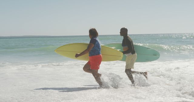 Senior african american couple running with surfboard on sunny beach - Download Free Stock Photos Pikwizard.com