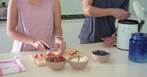 African american woman and asian man preparing fresh fruit breakfast in modern kitchen