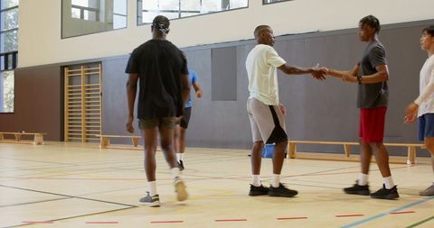 Men shaking hands on indoor basketball court celebrating teamwork and camaraderie