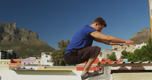 Man Performing Parkour Jump in Urban Area with Mountain Background - Download Free Stock Images Pikwizard.com