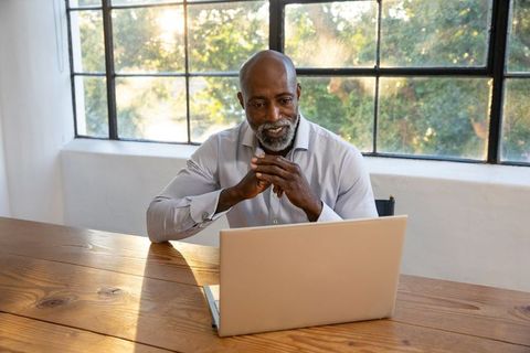 Mature Professional Man Working at Laptop in Sunlit Office