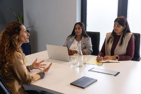 Diverse women leading job interview panel and discussing candidate in modern boardroom