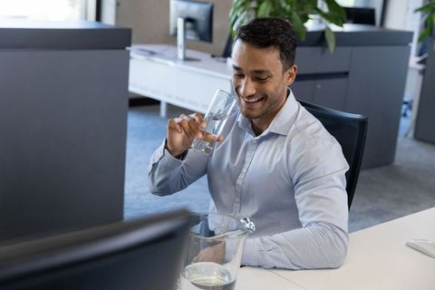Man at office desk taking a refreshing water break for productivity