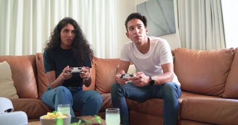 Young couple playing video game on living room couch competing in casual home gaming