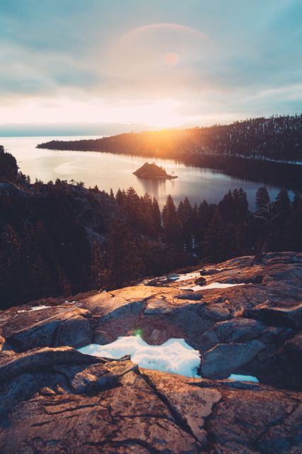 Serene sunset scene over Emerald Bay with a rocky foreground and an island in the middle of the tranquil water. Perfect for travel blogs, nature calendars, or environmental campaigns, reflecting the beauty and serenity of natural landscapes.