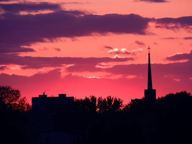 Silhouette of church steeple set against a vivid, colorful sunset sky. Clouds add depth and drama to the scene. Ideal for spiritual, tranquility, and nature themes or for backgrounds and presentations emphasizing sunsets and architecture.