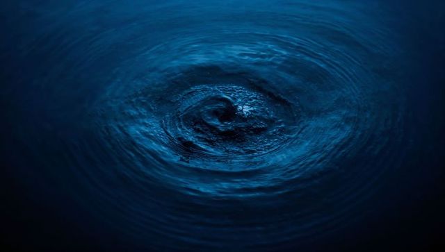Dark Blue Vortex with Concentric Ripples in Night Water