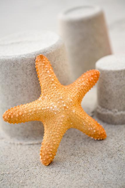 Close-up of three sand castles and starfish on tropical sand beach
