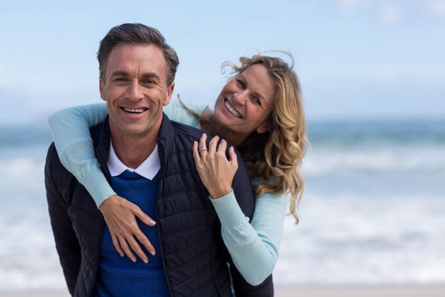 Portrait of mature man giving piggyback ride to woman on beach