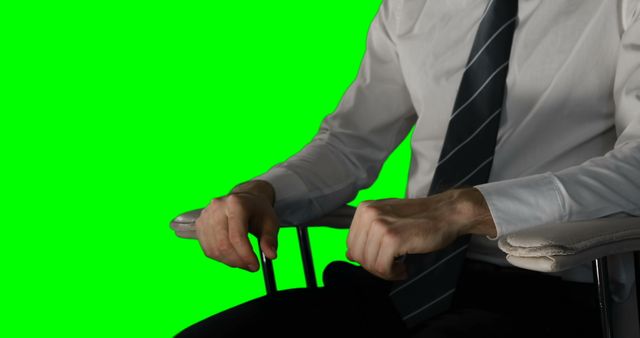 Businessman wearing suit and sitting on chair against green screen background. Perfect for corporate promotions, business presentations, or video projects needing a professional look or for using a custom backdrop.