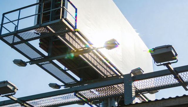 Glinting rooftop billboard and metal catwalk with floodlights and industrial railings