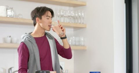 Young Man Drinking Pink Smoothie in Stylish Kitchen