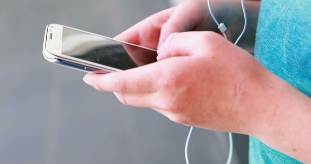 Close-up of Hands Holding Smartphone with Earphones - Download Free Stock Images Pikwizard.com