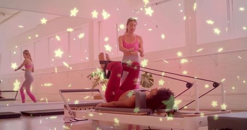 Pilates reformer leg workout with instructor guiding participant in bright daylight studio barre