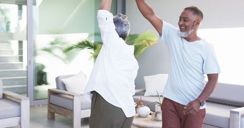 Happy Mature Couple Dancing in Modern Bright Living Room