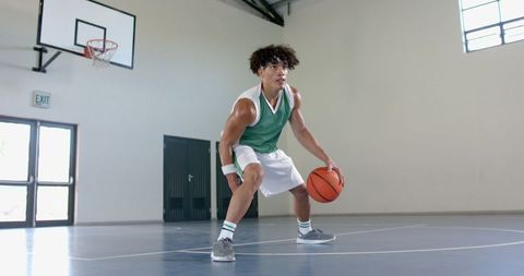 Young Athlete Focusing on Dribbling in Indoor Basketball Arena